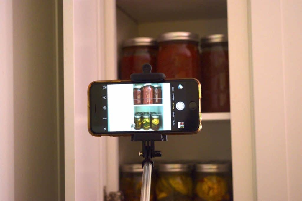 Phone mounted on a selfie stick taking a photo of a kitchen cabinet